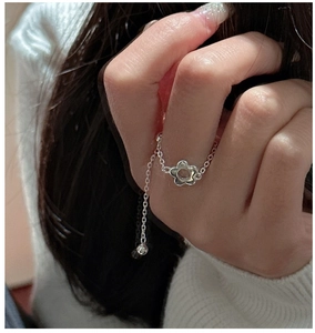 Gros plan d'une bague en argent sterling S925 avec un pendentif fleur délicat au doigt