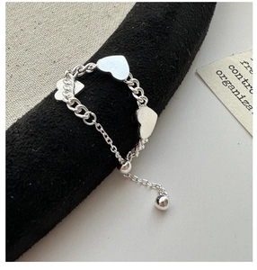 Détail d'une bague coeur ajustable en argent S925 sur un support noir