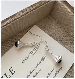 Macro shot of silver bell drop earrings with vertical texture and black agate beads