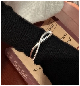 Close-up of a double-layered silver cross ring with polished and beaded textures on a hand