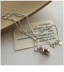 Macro view of 925 silver snowman pendant with colorful woven scarf and heart charm