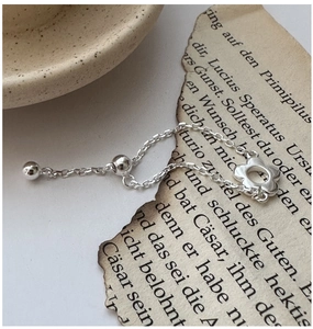 Détail d'une bague chaîne en argent S925 avec motif fleur et perle de réglage coulissante