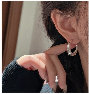 Gros plan de boucles d'oreilles créoles en argent sterling S925 poli sur une femme