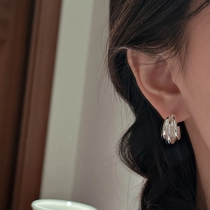 Elegant S925 sterling silver triple-layered wavy stud earrings worn by a female model