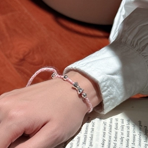 Bracelet S925 argent tressé rose avec pendentif nœud sur des pages de livre vintage