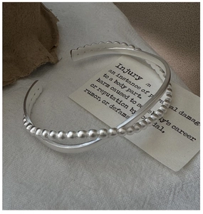 Detail of silver S925 double-layer open bangle with minimalist smooth and beaded textures