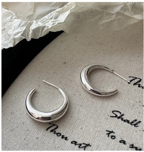 Vue détaillée des créoles polies en forme de C en argent sterling S925 sur toile