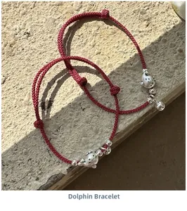 Vue détaillée de bracelets en corde rouge avec pendentifs dauphin argentés et grelots