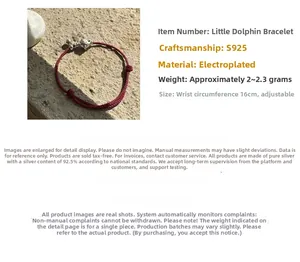Détail du bracelet en cordon rouge avec pendentif dauphin et clochettes en argent S925