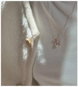 Detail of silver snowman pendant necklace with colorful thread on white cardigan