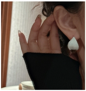 Détail d'une boucle d'oreille pétale en émail blanc portée par un mannequin