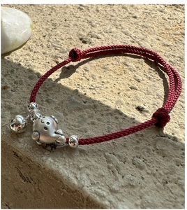 Vue détaillée du bracelet en corde rouge tressée avec pendentif dauphin et cloche