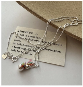 Close-up of S925 sterling silver beaded necklace with heart charm and colorful tassel bell