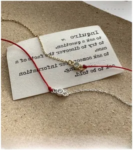 Detail of red string bracelets with minimalist silver and gold chains with zircon