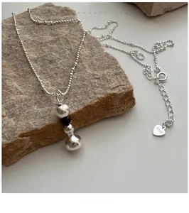 Détail du collier avec pendentif boule en argent sterling S925 sur une pierre naturelle