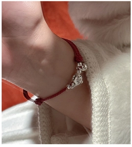 Gros plan d'un bracelet en corde tressée rouge avec dauphin en argent et clochettes
