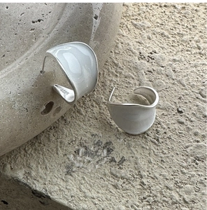 Détail des créoles en argent sterling S925 avec émail blanc sur une surface en pierre