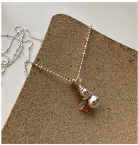 Macro detail of silver snowman necklace with colorful woven thread on a display board