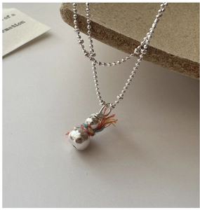 Detail of silver snowman pendant with colorful thread wrap on thin bead chain necklace