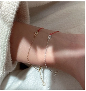 Macro shot of minimalist gold and silver red string bracelets with a single zircon stone