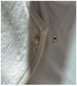 Détail du collier S925 en argent avec pendentif boule sur une tenue en maille blanche