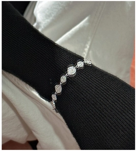 Macro shot of silver textured irregular disc bracelet on black ribbed knit sleeve