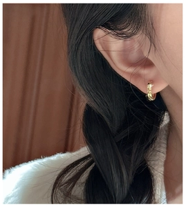 Gros plan d'une boucle d'oreille en argent S925 doré avec finition martelée sur modèle