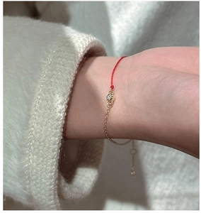 Detail of red string and gold chain bracelet with zircon stone on model wrist