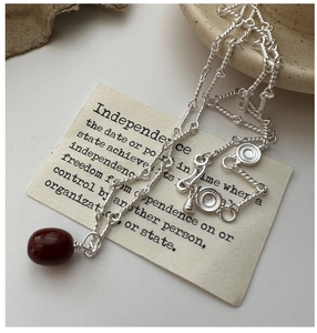 Close-up of S925 silver twisted chain necklace with a dark red gemstone pendant