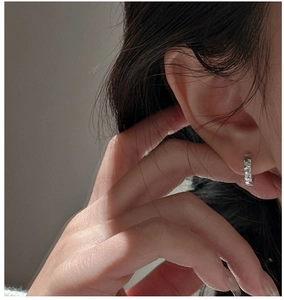 Gros plan de créoles en argent sterling S925 avec texture martelée portée par un modèle