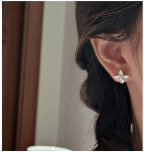 Close-up of matte silver leaf earrings with a pearl center worn on an ear