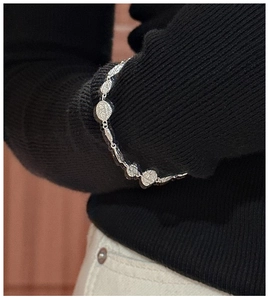 Detailed view of S925 sterling silver textured oval link bracelet on a dark knit sleeve
