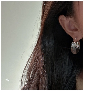 Gros plan d'un modèle portant les boucles d'oreilles en argent et résine en forme de U