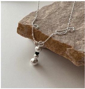 Détail du collier à pendentif boule en argent drapé sur une pierre brune sur fond gris