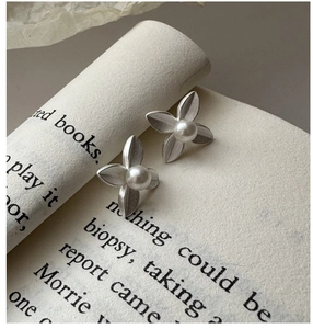 Detail of matte silver flower stud earrings with small white pearls on a vintage book