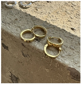 Gros plan de créoles en argent sterling S925 doré et argenté avec une texture martelée