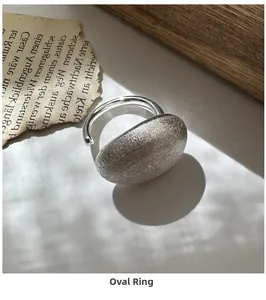 Gros plan d'une bague ovale en argent brossé mat sur un journal rétro sous la lumière