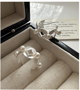 Macro shot of matte silver leaf earrings with pearls displayed in a vintage jewelry box