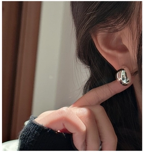 Detailed close-up of a minimalist silver teardrop earring with high-shine mirror finish