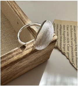 Vue détaillée d'une bague en argent S925 à texture brossée sur un plateau en bois