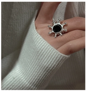 Macro shot of S925 silver sunburst ring with black agate inlay worn on a finger