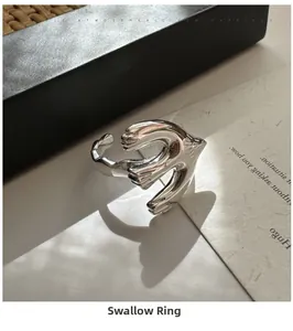 Macro detail of bird-shaped silver ring showing artistic swallow carving and shadows