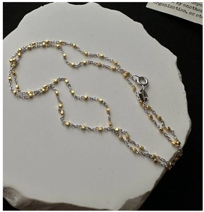 Close-up of S925 sterling silver spring clasp and bicolor chain texture on stone