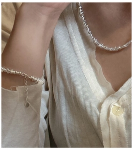 Close-up of silver irregular bead necklace and bracelet set on a model with knitwear