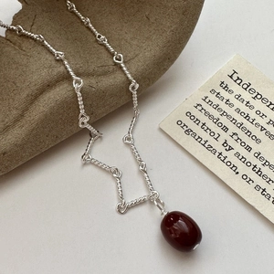 S925 sterling silver rope chain necklace with dark red agate pendant on a wooden stand