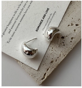 Macro shot of polished S925 sterling silver drop earrings on a stone background