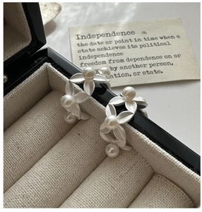 Macro detail of silver leaf earrings with pearls on a vintage jewelry display