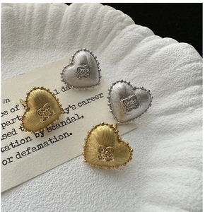 Macro shot of S925 silver heart stud earrings with brushed texture and zircon inlay