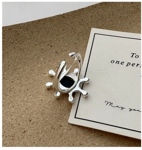 Detailed view of silver sunburst ring with black stone on aesthetic display card