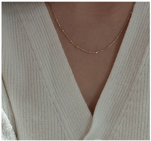 Close-up of a minimalist gold S925 sterling silver ball necklace worn on a woman